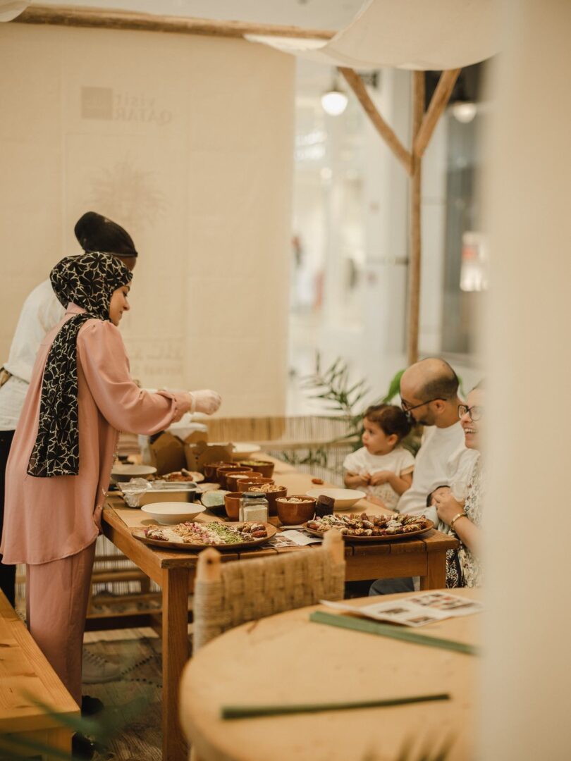 A host serving food to a family at a wooden table