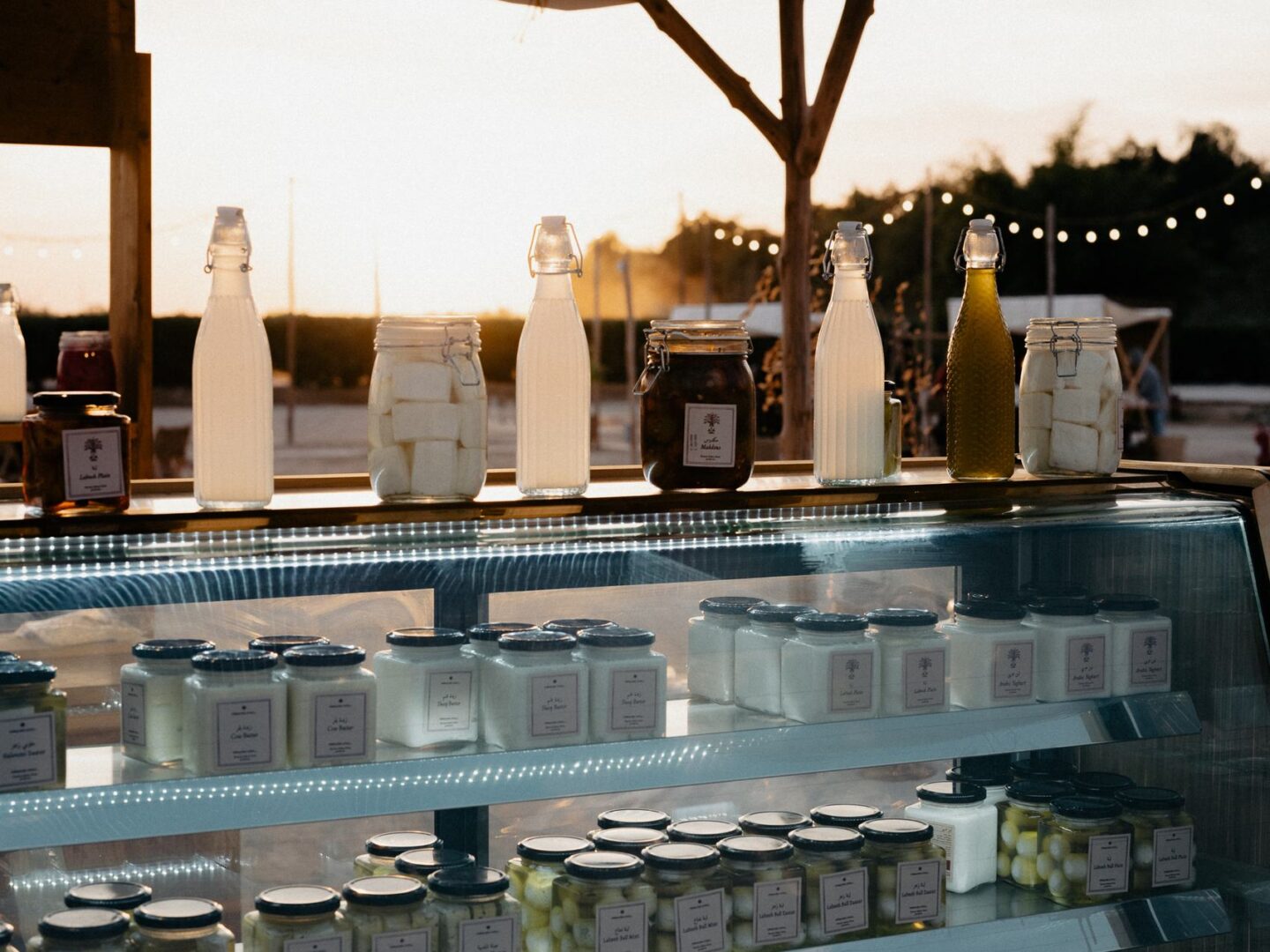 Glass jars and bottles of local produce lined up in a market display counter