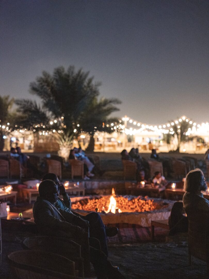 Guests gathered around a bonfire beneath palm trees at night