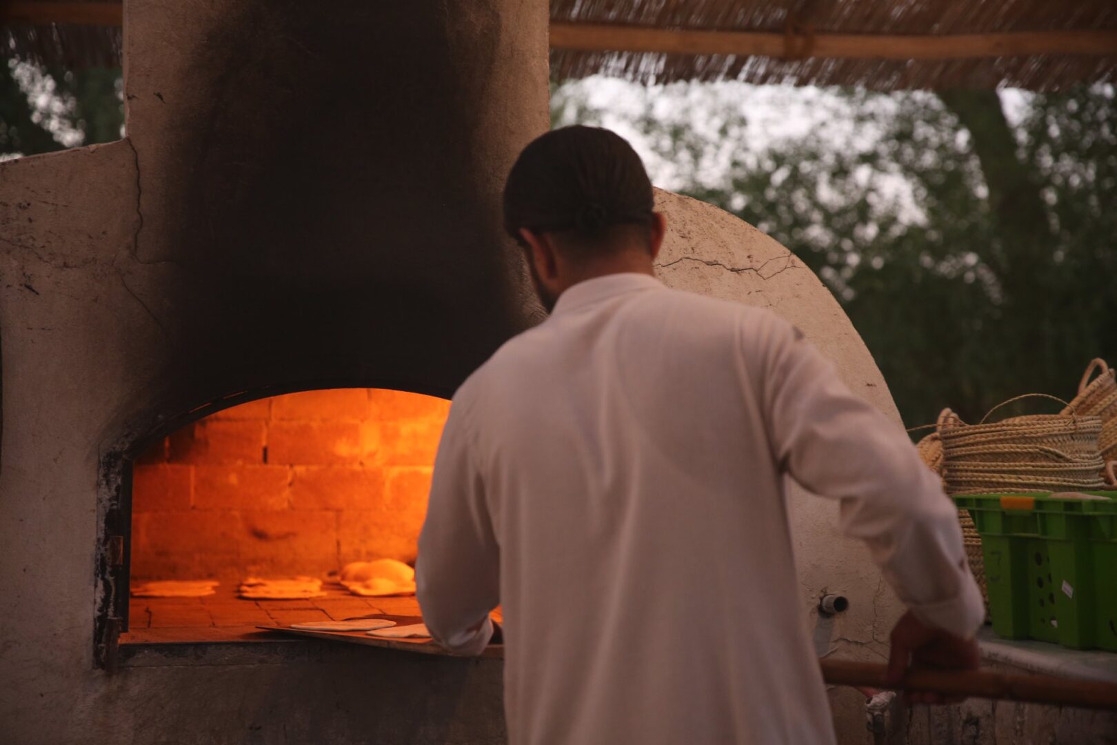 A cook tending the fire of a glowing dome oven
