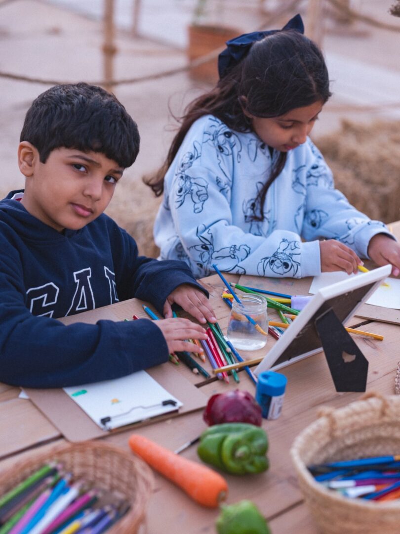 Two children drawing and making at a craft table